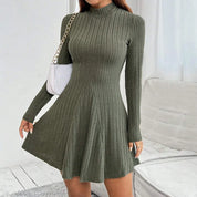 Vestito maglia a coste verde oliva, maniche lunghe, collo alto, abbinato a borsa bianca a catena. Elegante abbigliamento donna autunno.