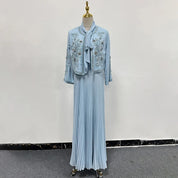 Abito lungo azzurro con giacca ricamata, manichino sartoriale, moda elegante, tessuto plissettato, abbigliamento donna, stile sofisticato.