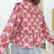 Blusa donna floreale rosa e rossa, maniche lunghe, colletto ampio, abbinata a jeans chiari. Moda femminile, abbigliamento casual elegante.