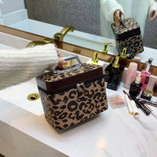 Borsa cosmetica leopardata su lavabo bagno, con cerniera e manico, accanto a trucchi e profumi. Design elegante, accessorio moda essenziale.