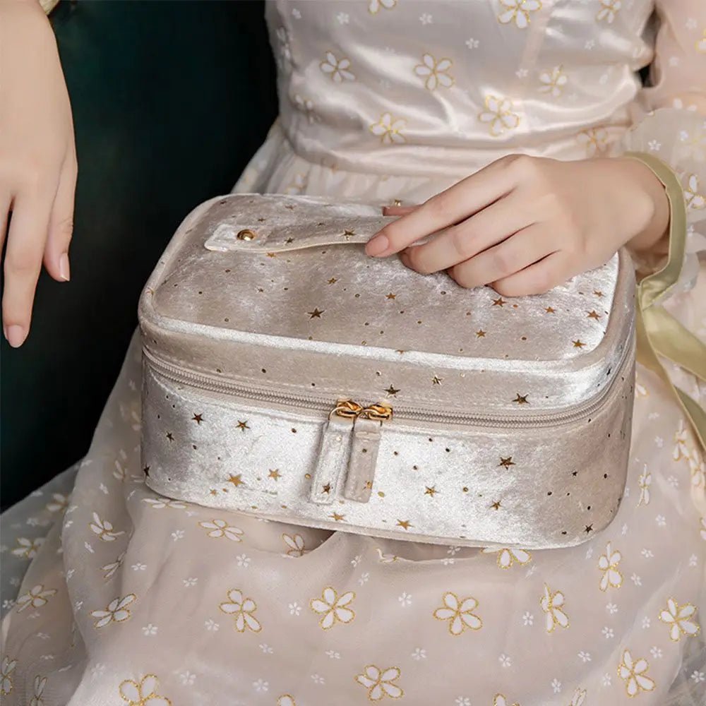 Astuccio cosmetico in velluto beige con stelle dorate, chiusura a zip, manico superiore. Elegante e spazioso, ideale per viaggi e organizzazione trucco.