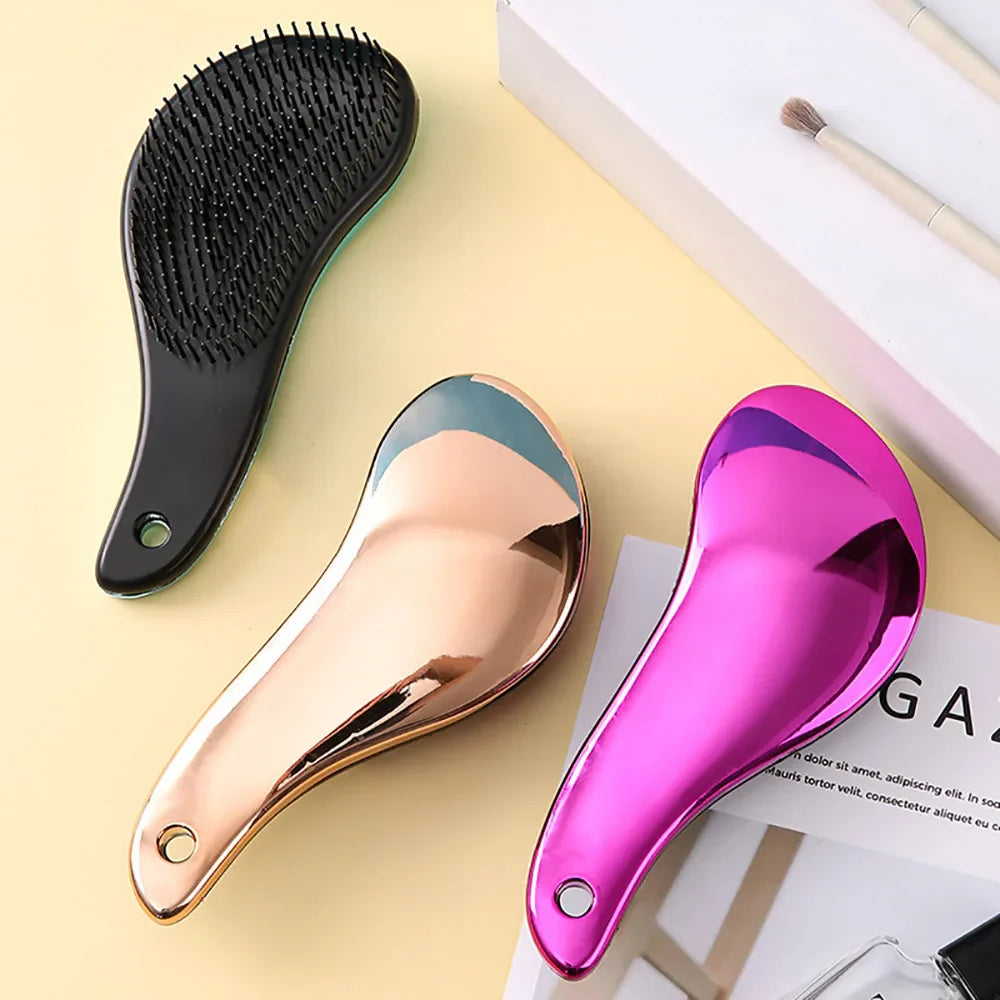 Tre spazzole districanti in plastica lucida, colori nero, oro e rosa, su sfondo bianco con pennelli da trucco. Accessori per capelli eleganti e funzionali.