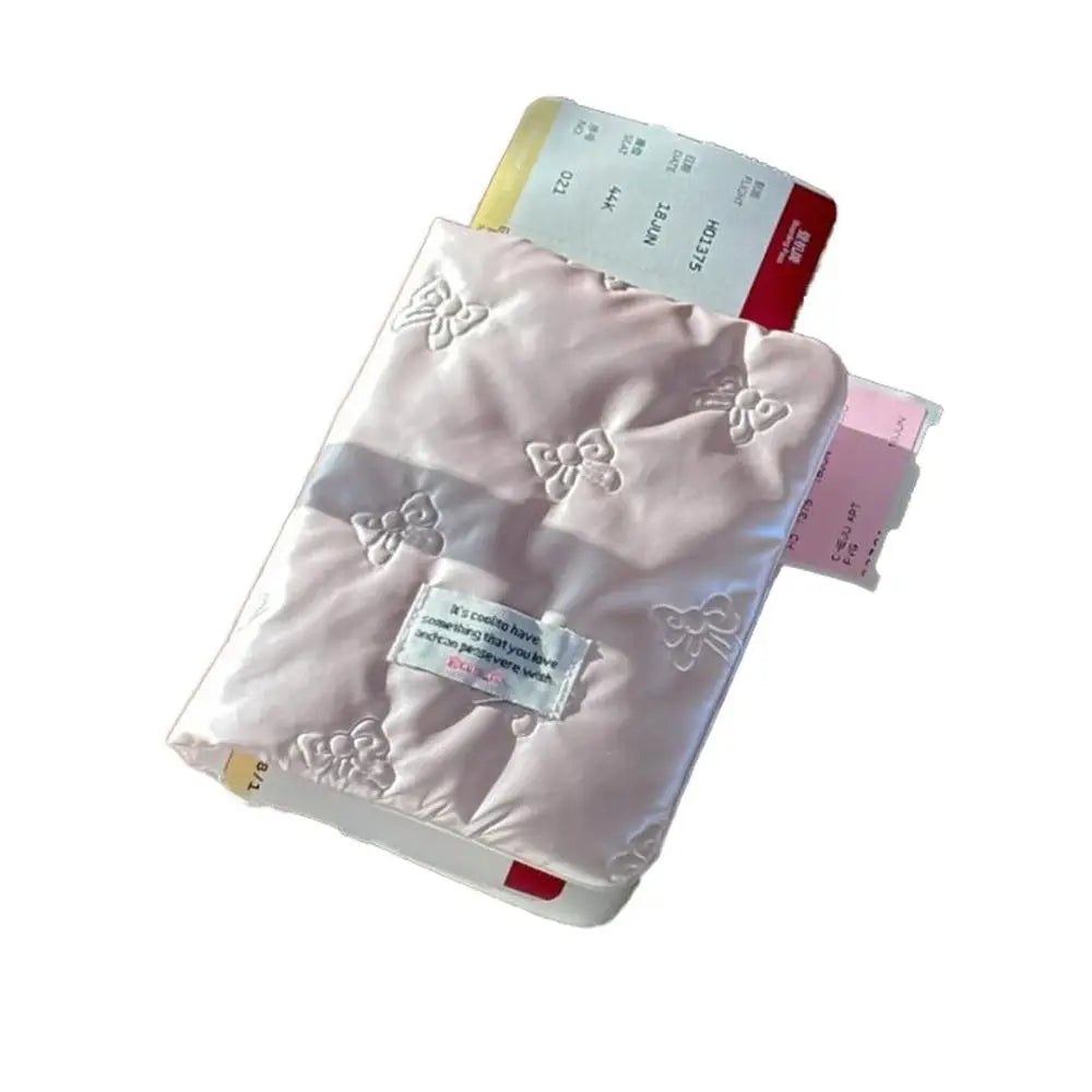 Custodia passaporto rosa trapuntata con motivi a farfalla, contenente biglietti aerei. Accessorio da viaggio elegante e funzionale.