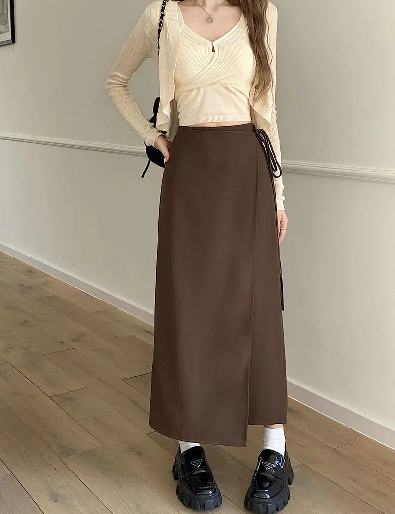 Gonna lunga marrone a portafoglio, abbinata a maglia beige a maniche lunghe e scarpe nere chunky. Moda donna autunno, stile casual elegante.