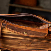 Borsa in pelle marrone aperta, con cerniera e tasca interna. Design elegante e artigianale, ideale per lavoro e viaggi. Accessorio moda uomo.