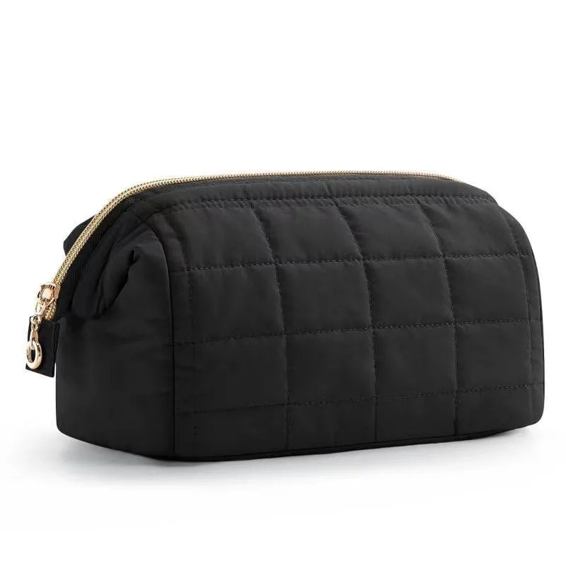 Astuccio da viaggio nero trapuntato con cerniera dorata, design elegante e spazioso, ideale per cosmetici e accessori. Perfetto per viaggi e uso quotidiano.