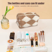 Borsa cosmetica in pelliccia sintetica a rombi beige e bianchi, con prodotti di bellezza e cura della pelle, pennelli trucco e flaconi su sfondo chiaro.