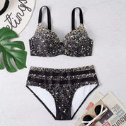 Costume da bagno bikini nero con stampa a pois dorati, reggiseno imbottito e slip a vita alta. Accessori: occhiali da sole, cappello, foglia decorativa.