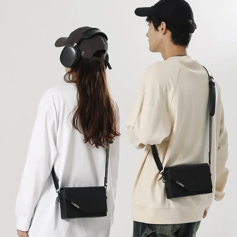 Due persone con borse a tracolla nere, abbigliamento casual, cappelli e cuffie. Moda urbana, accessori unisex, stile contemporaneo.