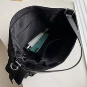 Borsa a tracolla nera aperta con tasca interna, contenente una bottiglia d'acqua e uno smartphone verde. Design elegante e spazioso.