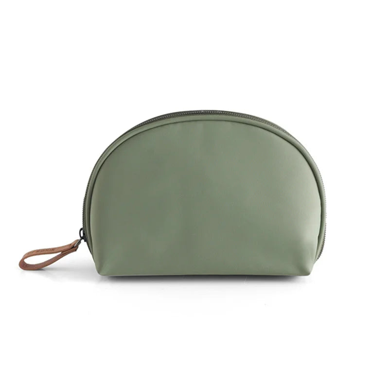 Astuccio cosmetico verde oliva in pelle sintetica, forma semicircolare, con cerniera e manico in pelle marrone. Accessorio moda elegante e pratico.
