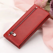 Portafoglio donna in pelle rossa con cerniera, elegante e moderno, su sfondo di tessuto rosa. Accessorio moda, regalo perfetto.
