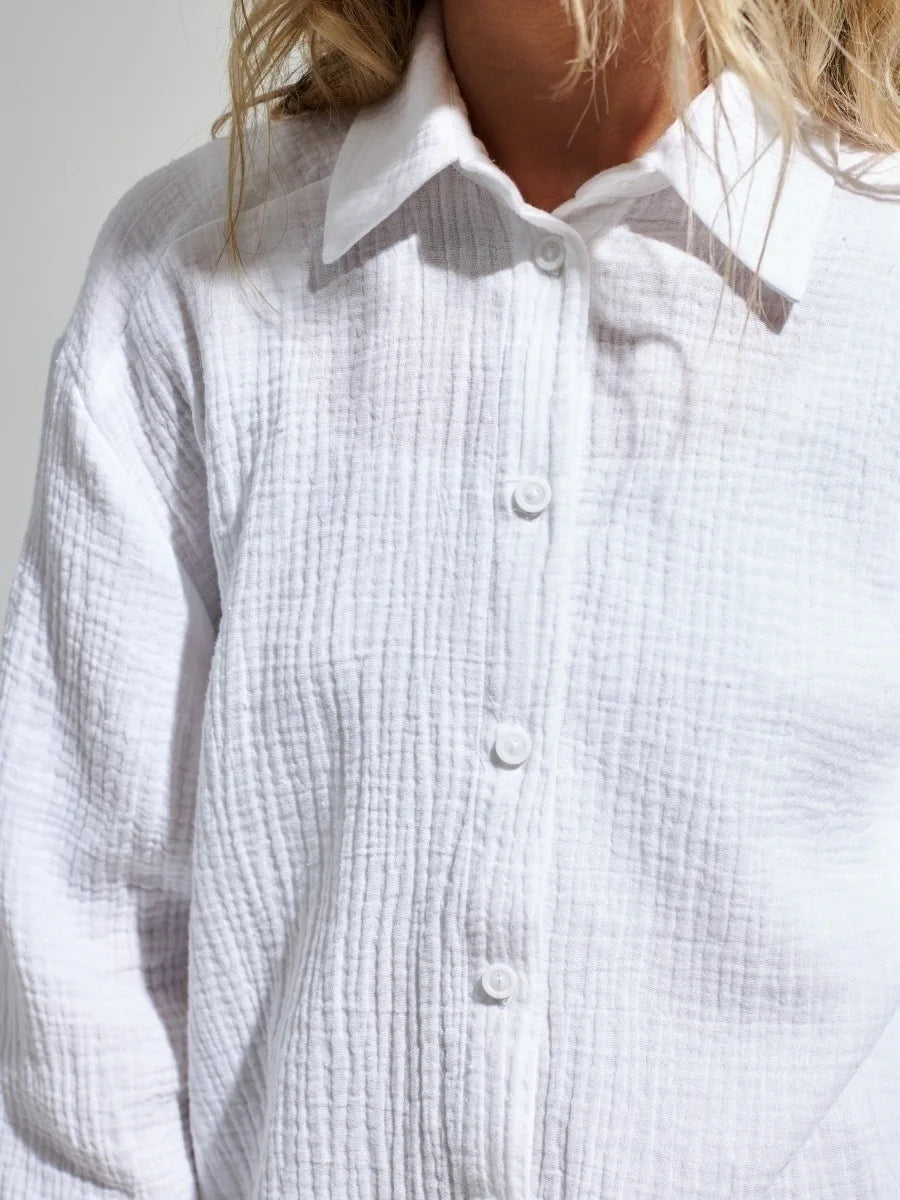 Camicia bianca in cotone a maniche lunghe, tessuto a quadri, colletto classico, bottoni frontali. Moda donna, abbigliamento casual elegante.