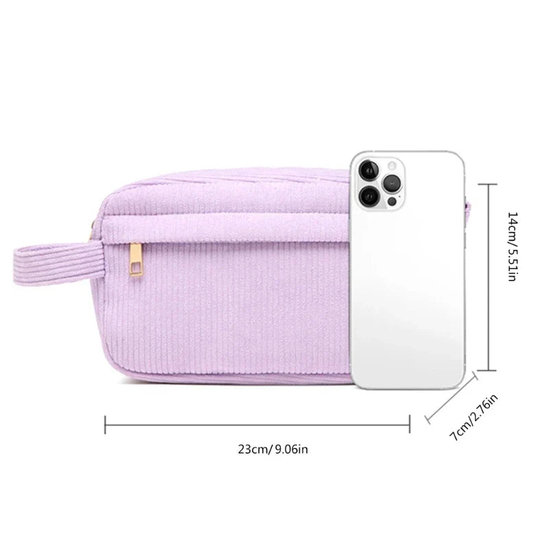 Astuccio in velluto a coste lilla con zip, dimensioni 23x7x14 cm, accanto a uno smartphone bianco per confronto. Accessorio moda pratico ed elegante.
