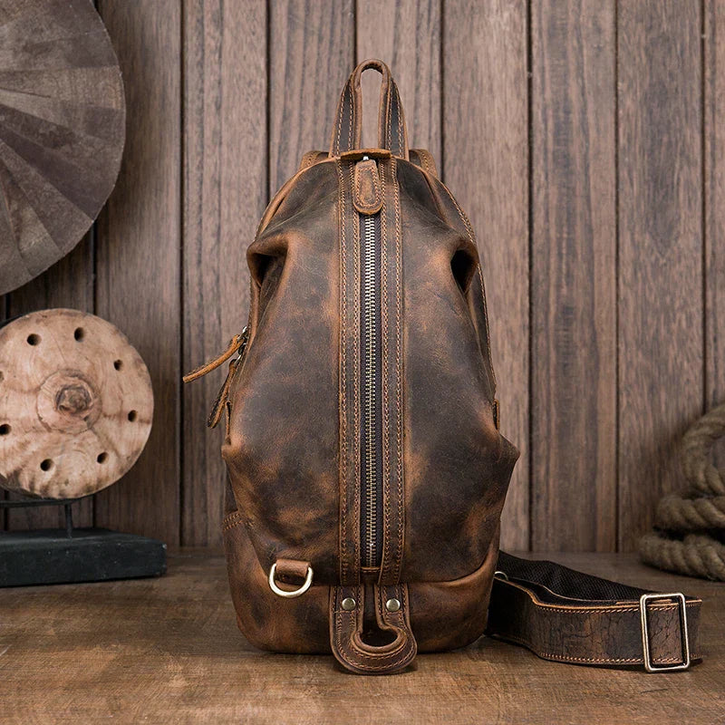 Zaino in pelle vintage marrone con cerniera centrale, stile retrò, su sfondo di legno. Ideale per viaggi e uso quotidiano. Accessorio moda uomo.