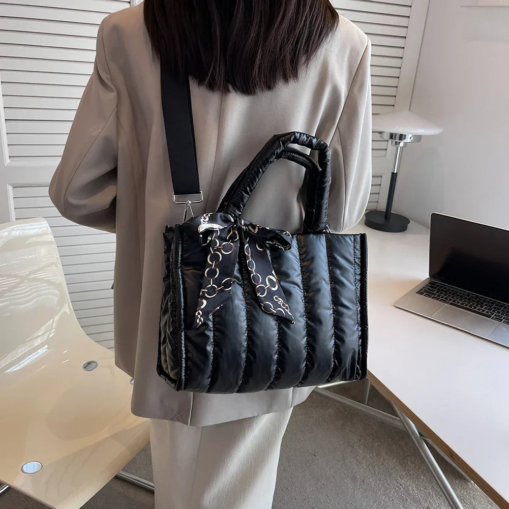Donna con borsa a tracolla nera imbottita, dettagli a catena, in ufficio moderno. Moda elegante, accessori femminili, stile contemporaneo.