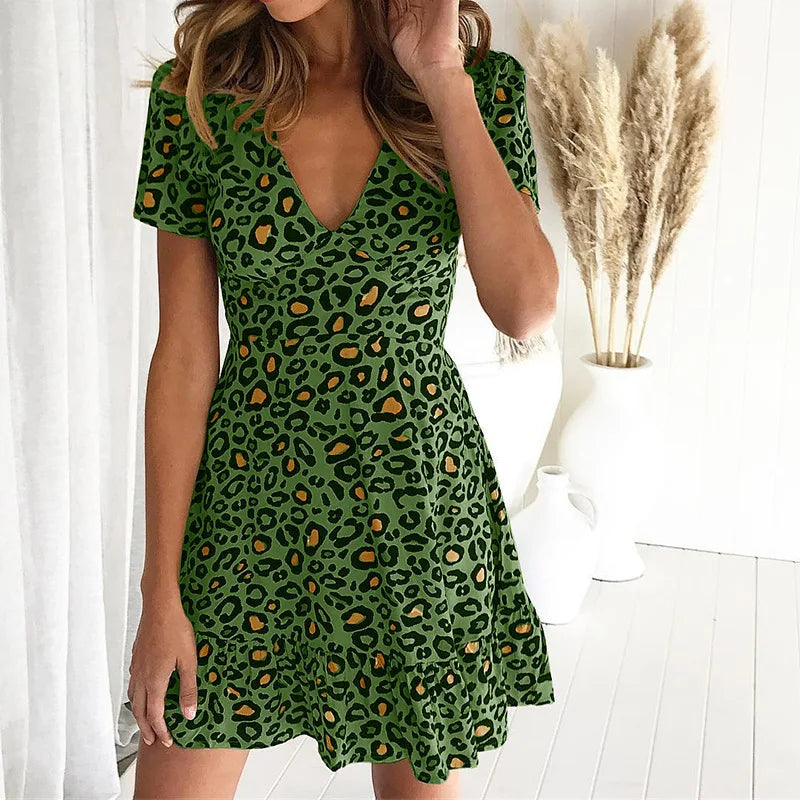 Abito corto verde leopardato con scollo a V, maniche corte, sfondo bianco, decorazione pampas. Moda donna, stile casual elegante.
