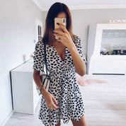 Donna in abito estivo bianco e nero a pois, scatta selfie in soggiorno moderno. Moda femminile, abbigliamento casual, tendenze 2023.