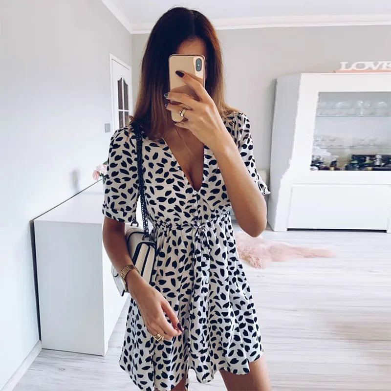 Donna in abito estivo bianco e nero a pois, scatta selfie in soggiorno moderno. Moda femminile, abbigliamento casual, tendenze 2023.
