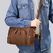 Borsa a tracolla in pelle marrone, indossata da una persona con camicia di jeans. Design elegante, ideale per uomo, moda casual.