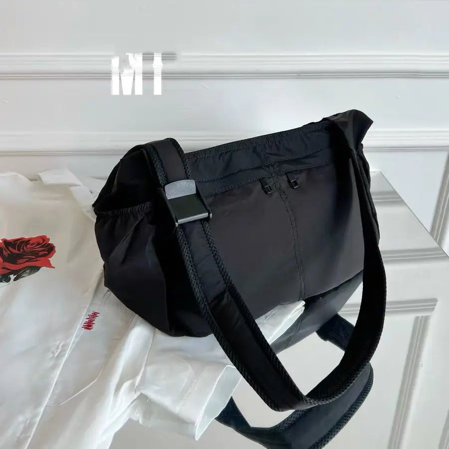 Borsa a tracolla nera su tavolo riflettente, design elegante e minimalista, perfetta per moda donna, accessorio versatile e moderno.