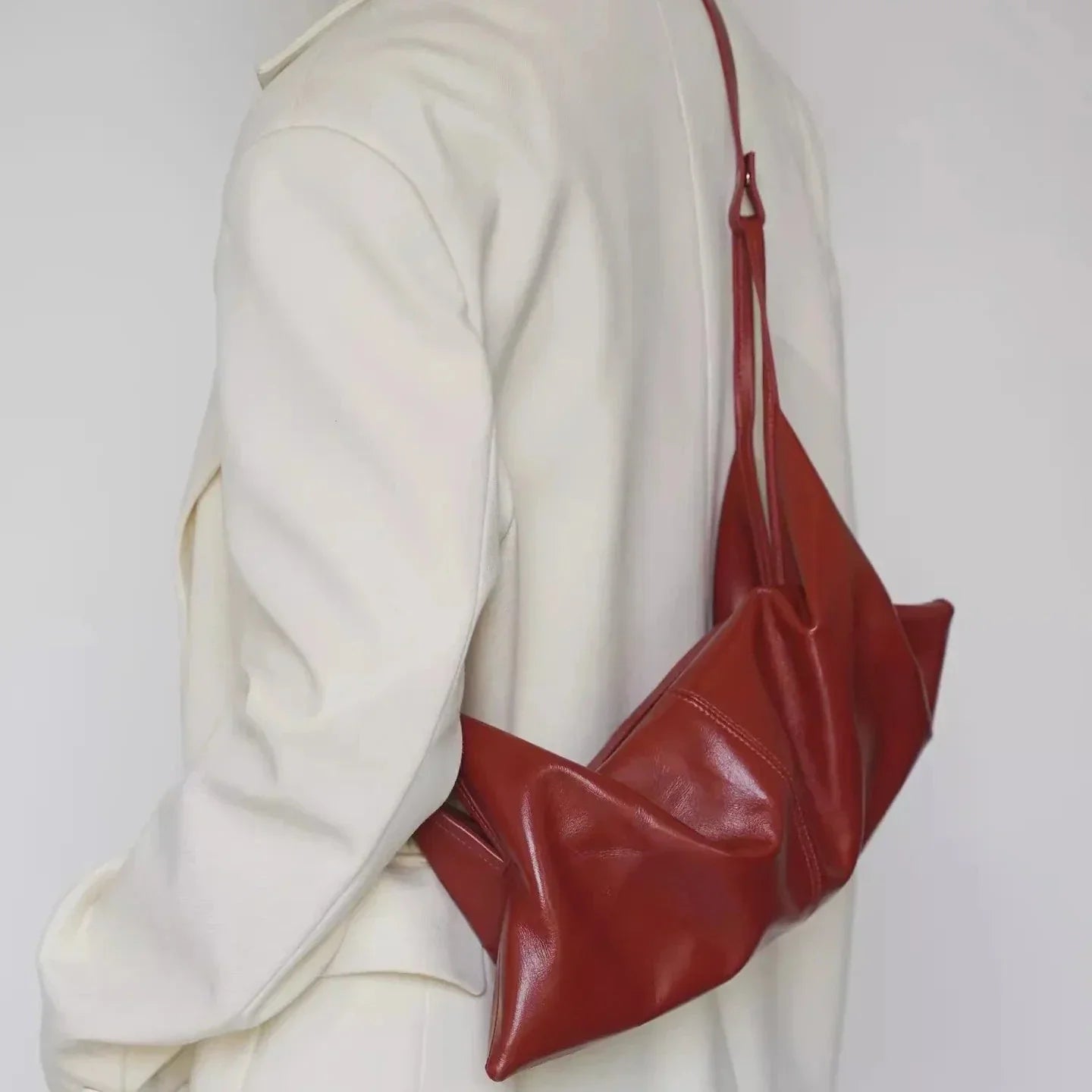 Borsa a tracolla in pelle rossa su cappotto bianco, design moderno ed elegante. Accessorio moda donna, stile minimalista e chic.
