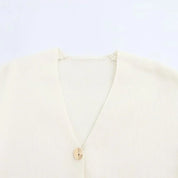 Cardigan beige in maglia a coste con scollo a V e bottone singolo. Elegante e versatile, ideale per look casual e formali.