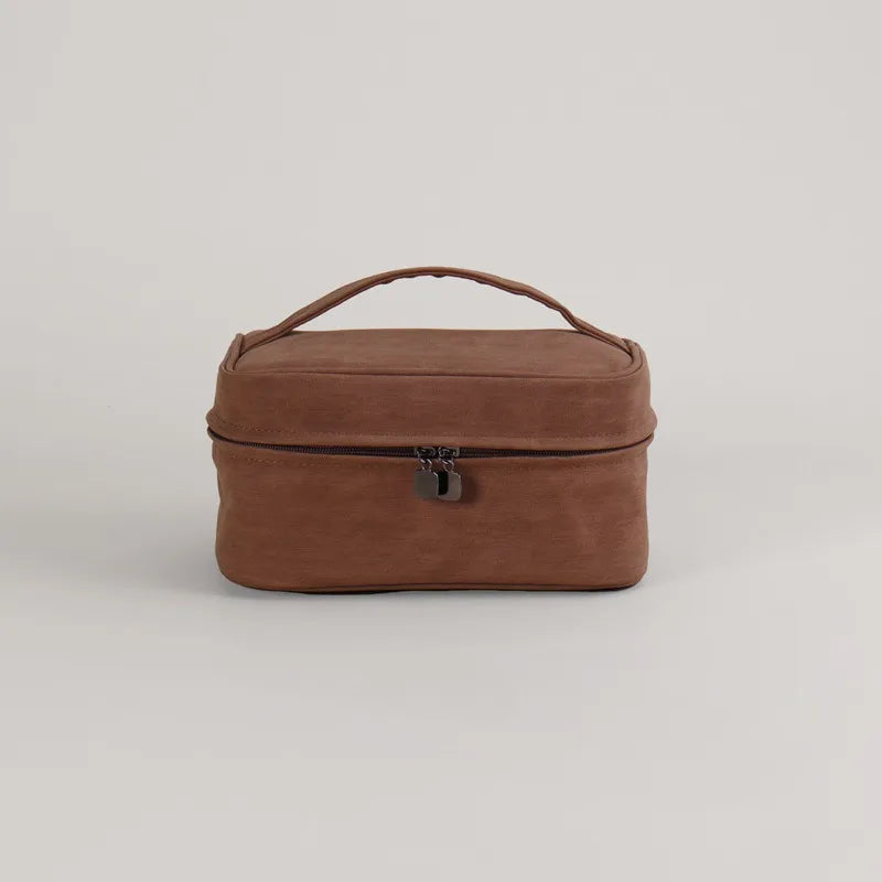 Astuccio da viaggio in pelle marrone con manico, chiusura a zip e doppio cursore. Elegante e pratico per cosmetici e accessori.
