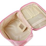 Astuccio cosmetico rosa aperto, con scomparti interni beige e specchietto. Ideale per organizzare trucchi e accessori da viaggio.