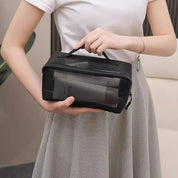 Donna con borsa da toilette trasparente nera, contenente flaconi da viaggio. Ideale per organizzare cosmetici e accessori. Perfetta per viaggi e uso quotidiano.