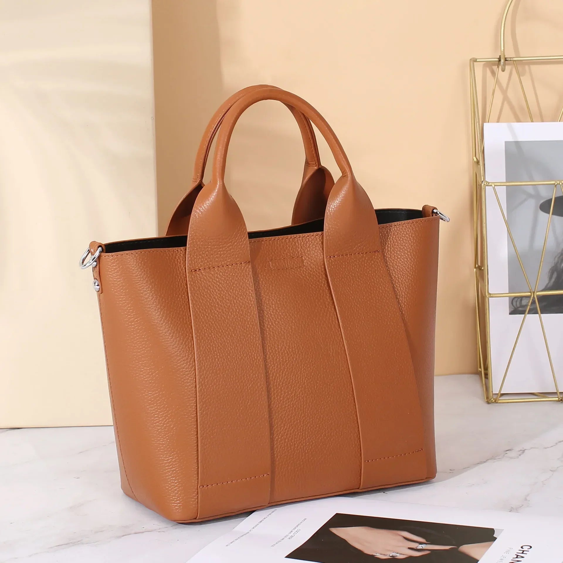 Borsa a mano in pelle marrone su sfondo chiaro, design elegante e moderno, ideale per moda femminile, accessorio di tendenza per ogni occasione.