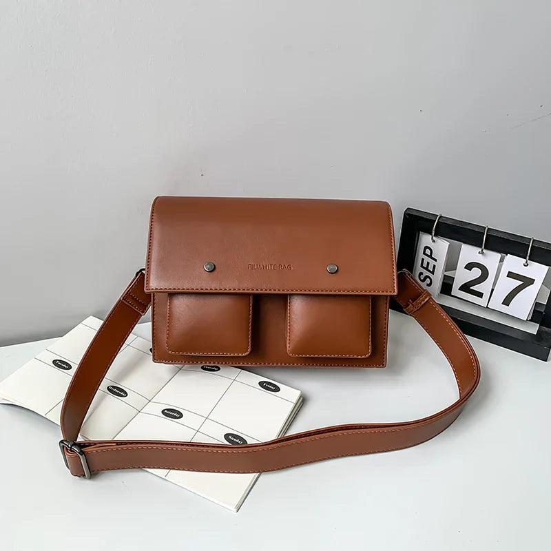 Borsa a tracolla in pelle marrone con due tasche frontali, design elegante e moderno, perfetta per l'uso quotidiano. Accessorio moda autunno.