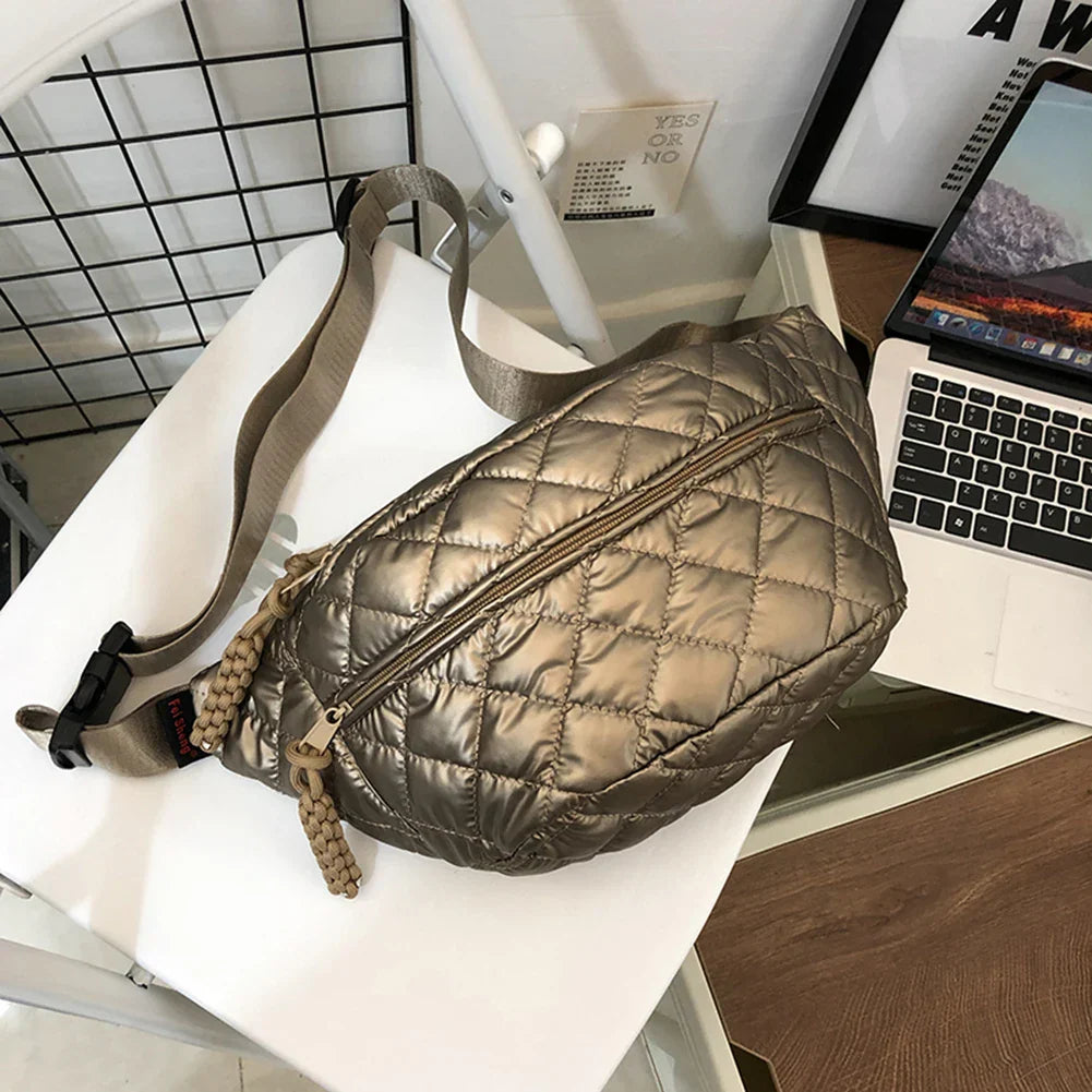 Marsupio trapuntato color bronzo su sedia bianca, con cerniera e cinturino regolabile. Accessorio moda unisex, ideale per viaggi e attività all'aperto.