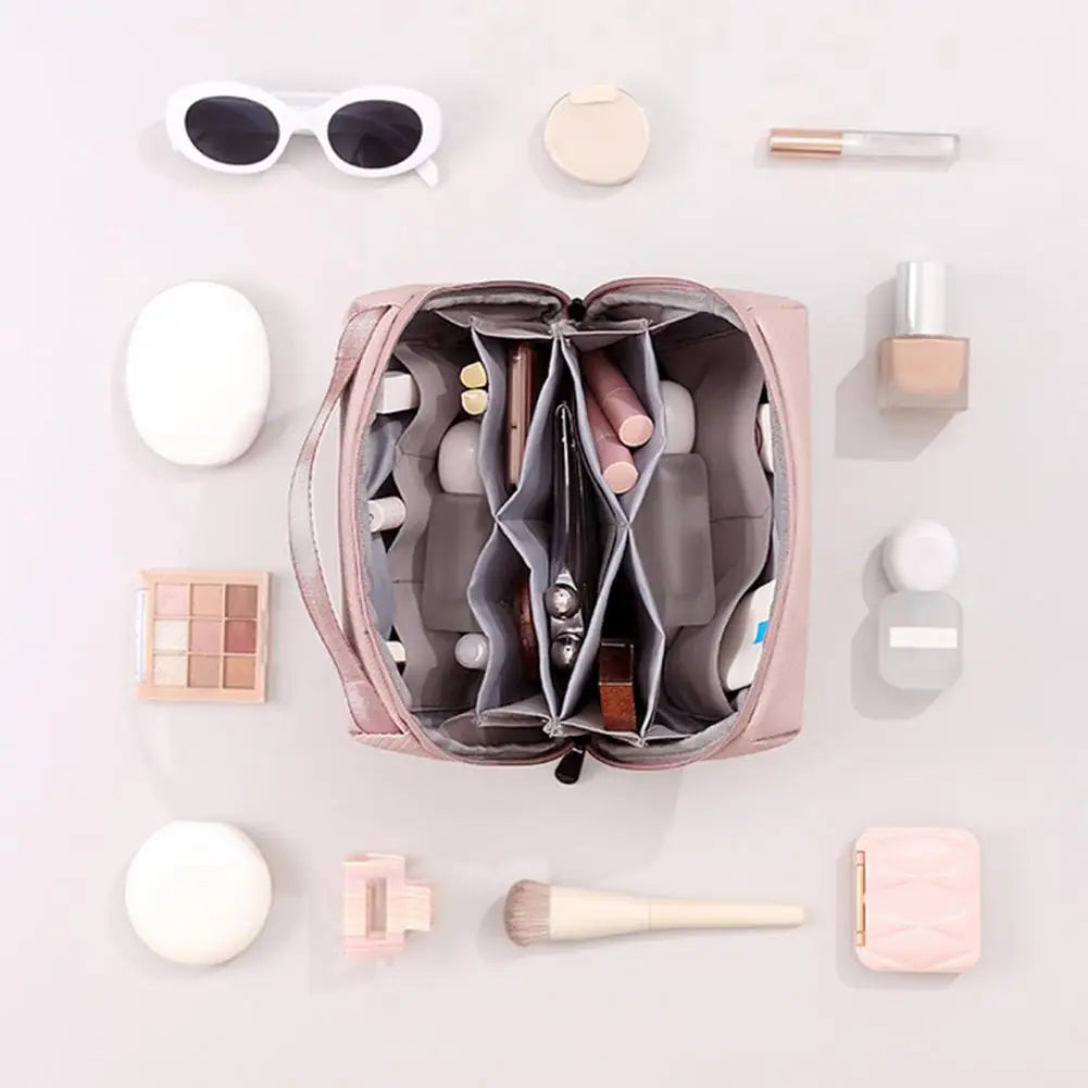 Borsa trucco rosa aperta con scomparti organizzati, circondata da cosmetici: occhiali da sole, ombretti, pennello, rossetto. Accessori beauty.