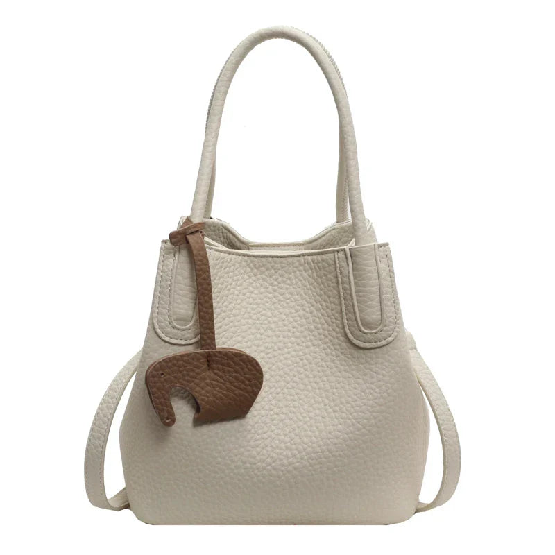 Borsa a mano in pelle bianca con texture, decorazione marrone a forma di elefante, manici doppi, design elegante e moderno. Accessorio moda donna.