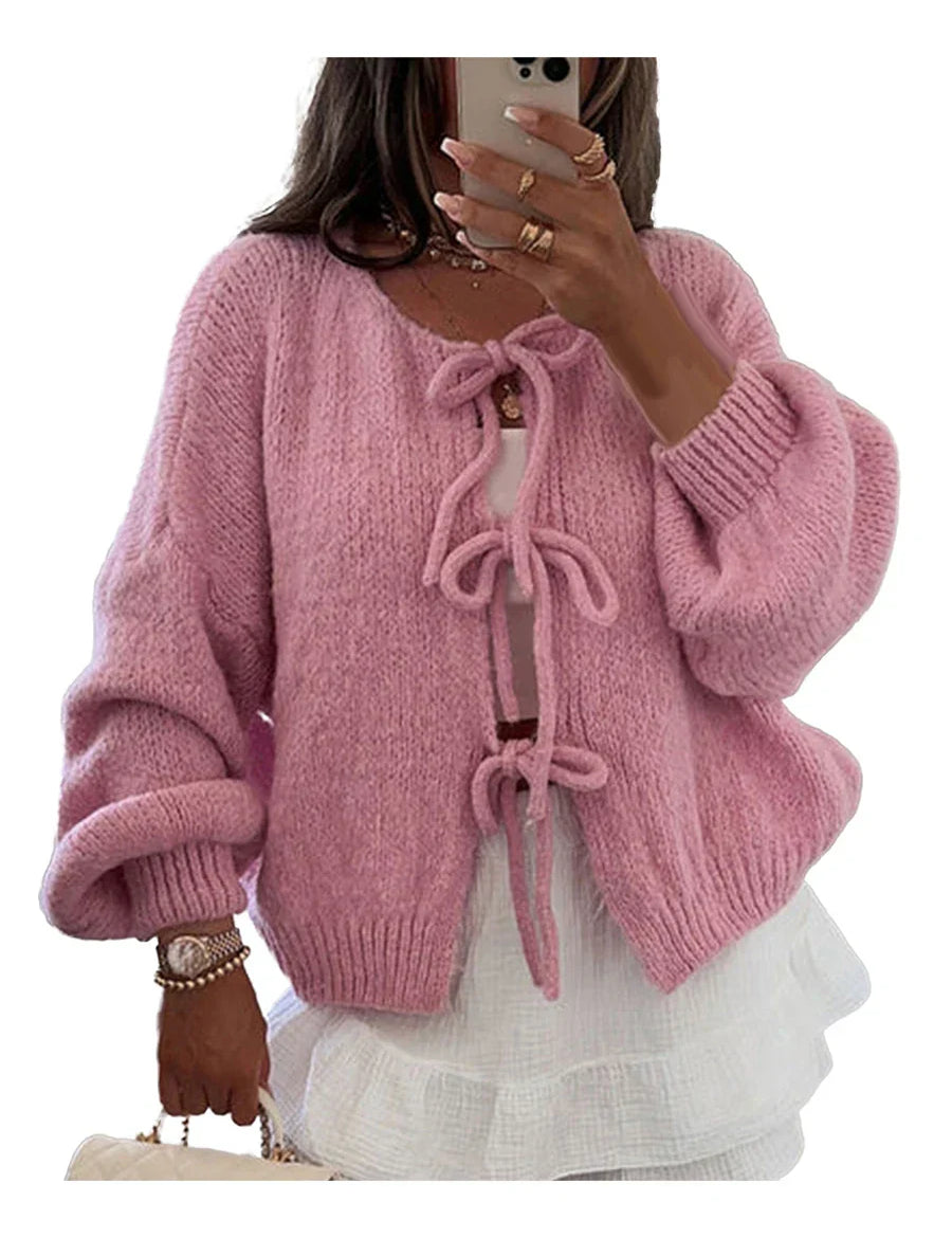 Cardigan rosa in maglia con fiocchi, maniche lunghe e design morbido. Perfetto per moda autunnale e invernale. Donna che indossa accessori eleganti.