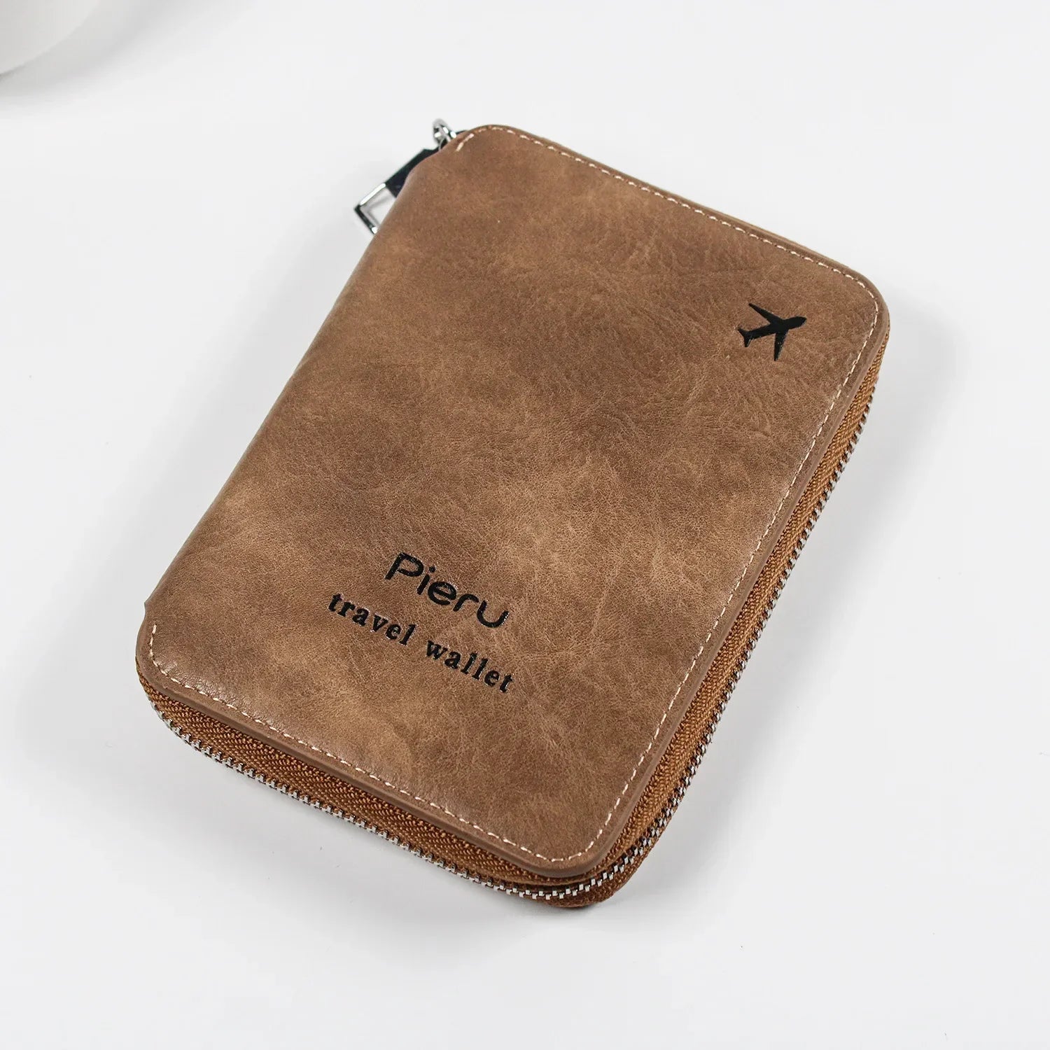 Portafoglio da viaggio in pelle marrone con cerniera, logo "Pieru" e icona aereo. Elegante e funzionale, ideale per viaggiatori.