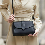 Borsa a tracolla nera elegante in pelle, indossata da una donna in abito beige. Accessorio moda femminile, stile classico e versatile.