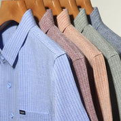 Camicie eleganti da uomo in cotone, a righe, colori assortiti, appese su grucce di legno. Ideali per ufficio e occasioni formali.