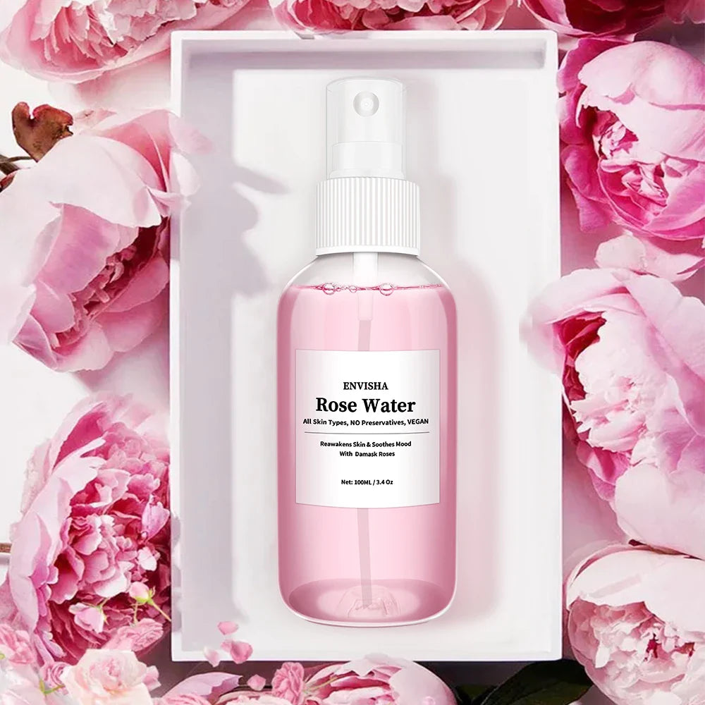 Spray acqua di rose Envisha 100ml, flacone trasparente, su sfondo di fiori rosa. Idratante viso, vegano, senza conservanti. Adatto a tutti i tipi di pelle.