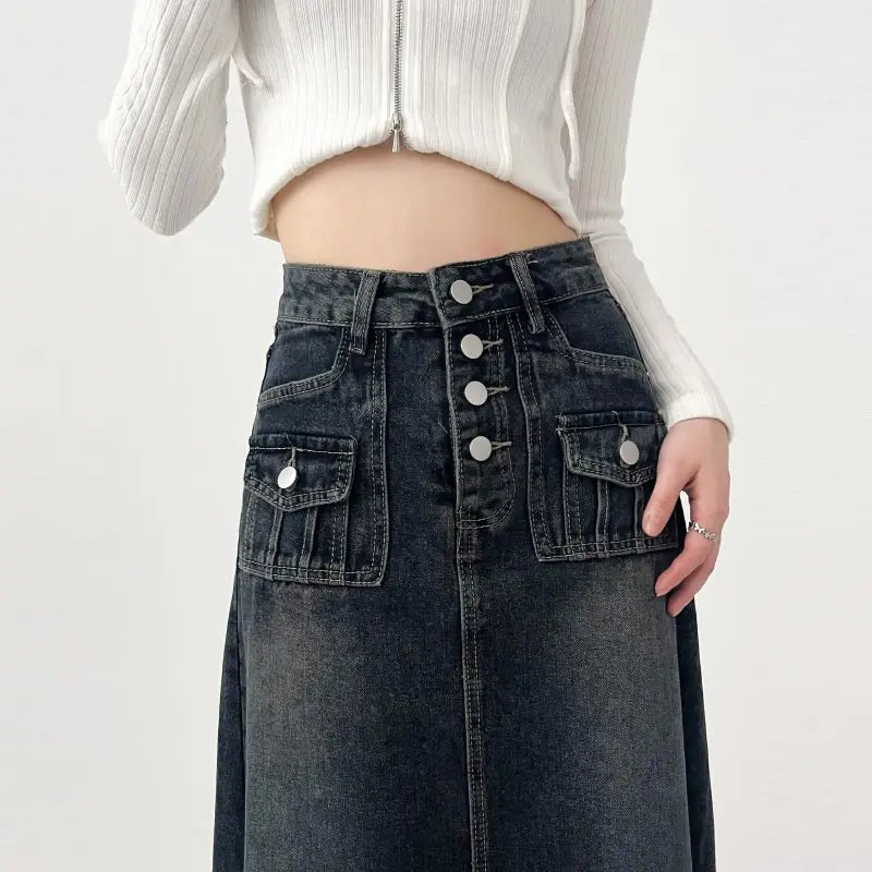 Gonna lunga in denim nero con bottoni, tasche frontali, abbinata a top bianco a coste. Moda casual donna, abbigliamento trendy autunno.