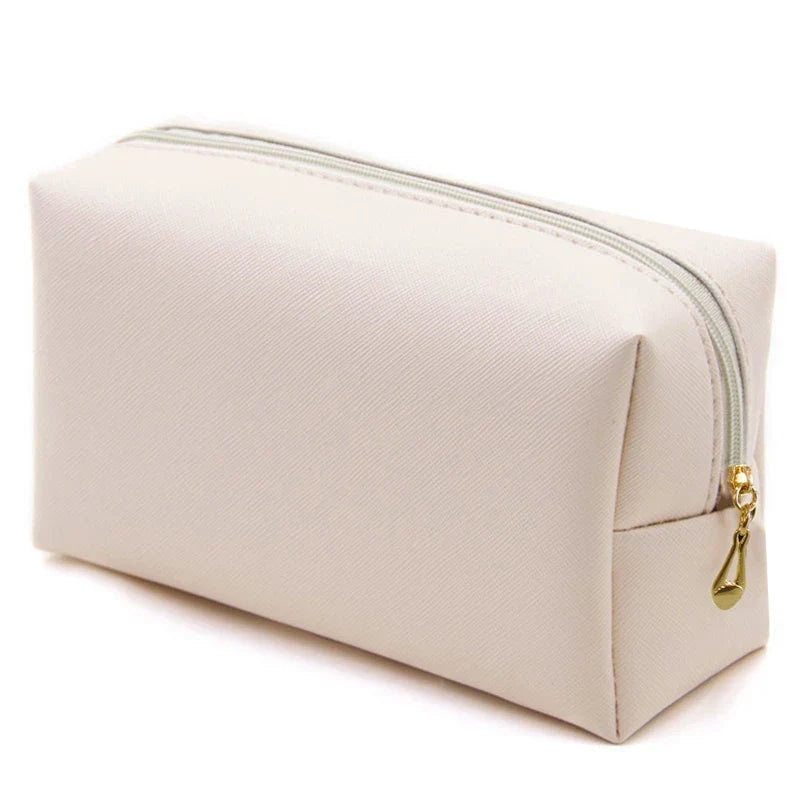 Astuccio cosmetico beige in tessuto, chiusura con cerniera dorata, design minimalista. Ideale per trucco e accessori da viaggio.