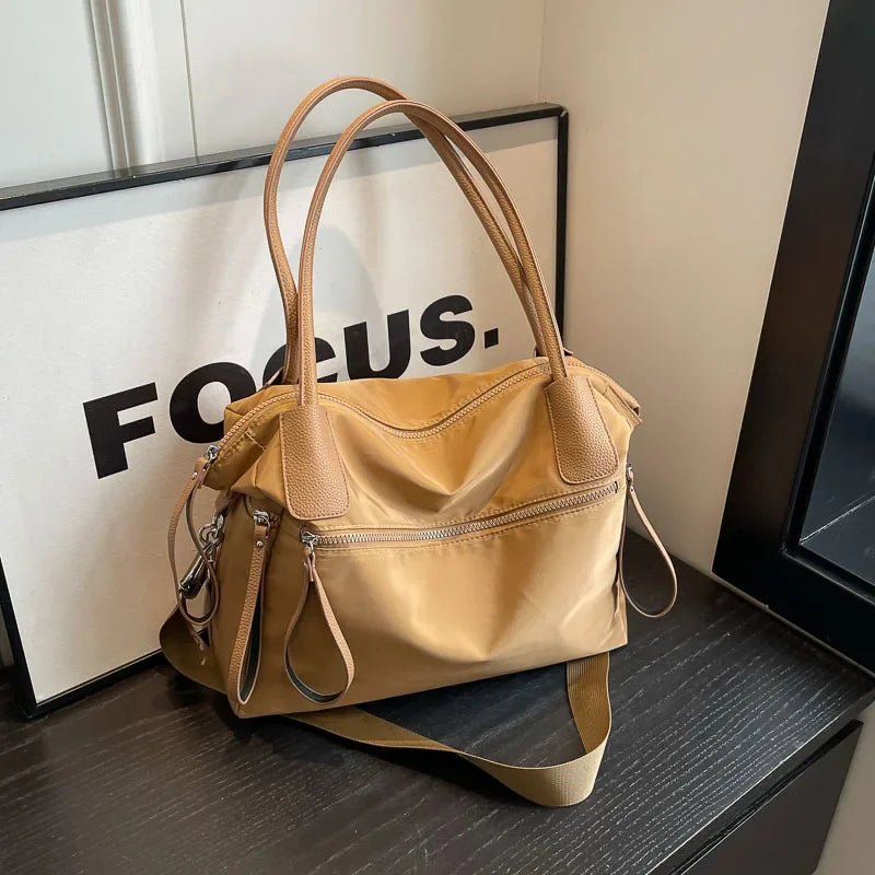 Borsa a mano beige su tavolo nero, design elegante con manici in pelle marrone, perfetta per moda donna, accessorio versatile e chic.