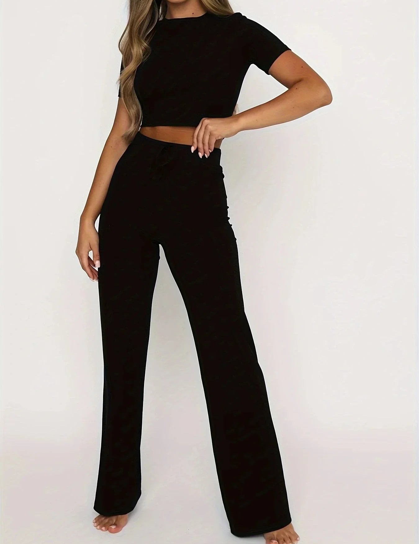 Donna in completo nero elegante, top corto e pantaloni a vita alta. Abbigliamento moda donna, stile casual chic, perfetto per ogni occasione.