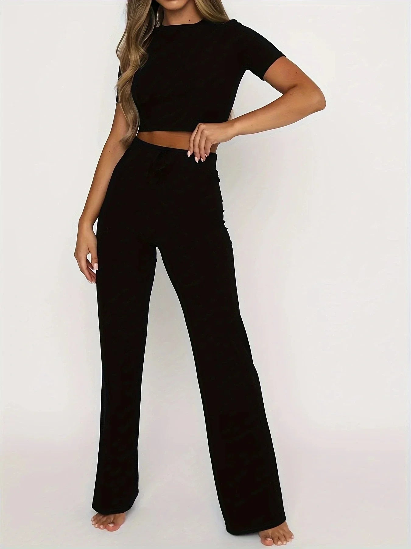 Donna in completo nero elegante, top corto e pantaloni a vita alta. Abbigliamento moda donna, stile casual chic, perfetto per ogni occasione.