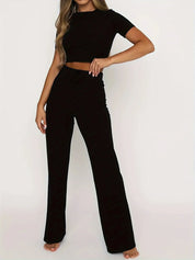Donna in completo nero elegante, top corto e pantaloni a vita alta. Abbigliamento moda donna, stile casual chic, perfetto per ogni occasione.