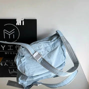 Borsa a tracolla azzurra con cinturino regolabile, design moderno, su sfondo bianco e nero. Accessorio moda versatile per donna.