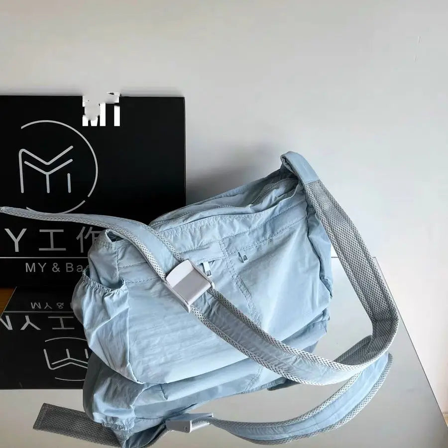Borsa a tracolla azzurra con cinturino regolabile, design moderno, su sfondo bianco e nero. Accessorio moda versatile per donna.