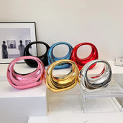 Sculture decorative moderne in ceramica colorata, design astratto, colori oro, argento, rosso, blu e rosa, su mensola bianca, arte contemporanea.