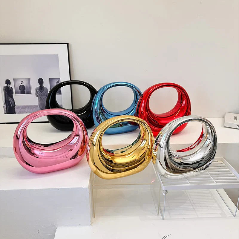 Sculture decorative moderne in ceramica colorata, design astratto, colori oro, argento, rosso, blu e rosa, su mensola bianca, arte contemporanea.